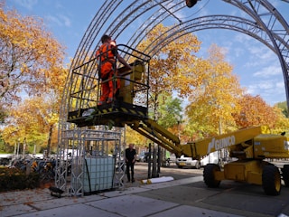 A truck with a basket lifting a worker trimming tall trees.