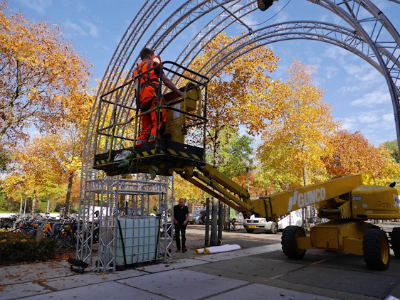 Technician inspecting a scissor lift on a sunny job site, showcasing hands-on care.