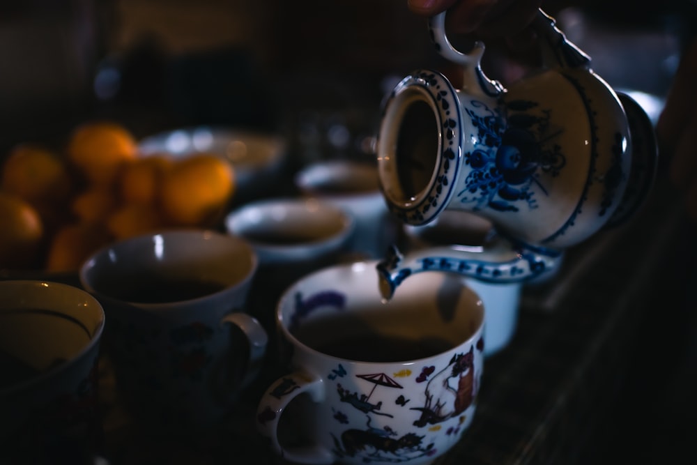 a person pours a cup of tea from a teapot