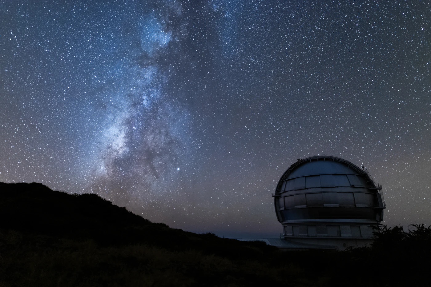 Telescopio su un crinale, via lattea bassa all'orizzonte