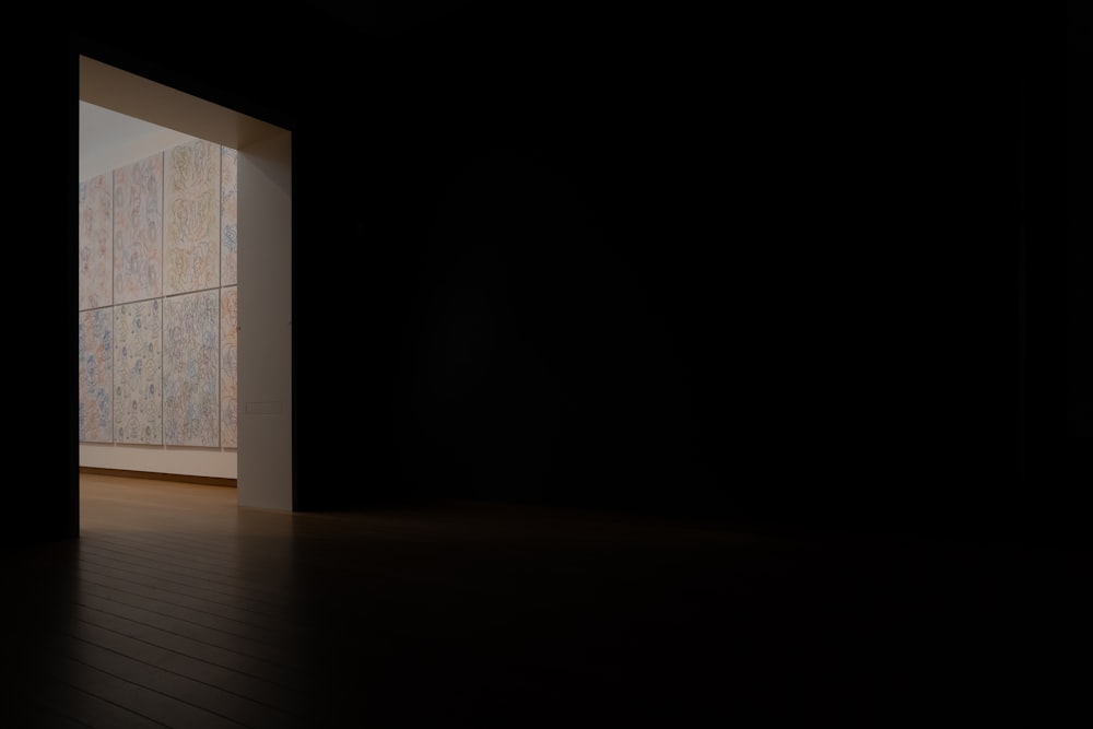 una porta aperta in una stanza buia con un pavimento in legno