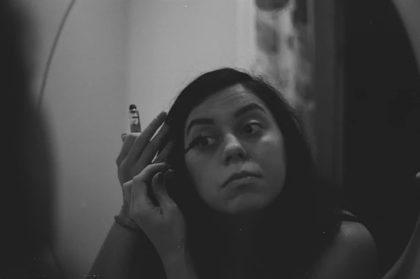 Model applying Santa’s signature black and gold mascara in soft natural light.