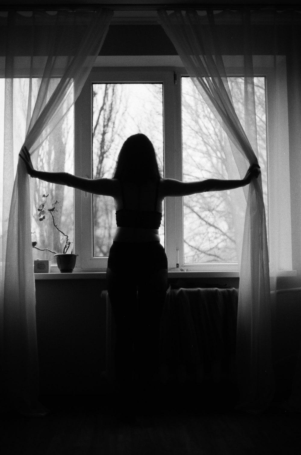 a woman standing in front of a window with her arms outstretched