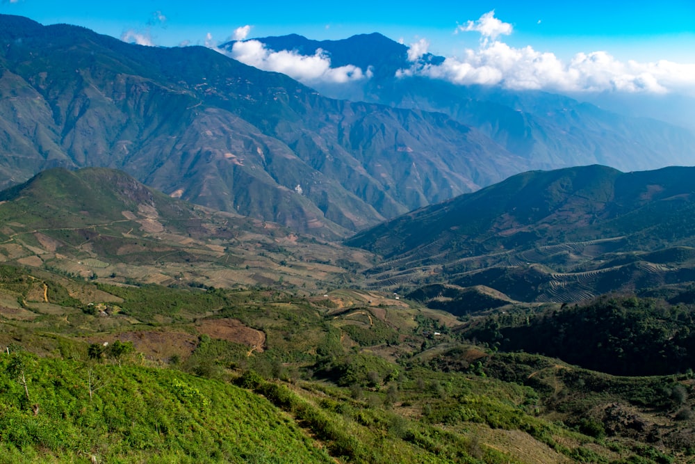 montanhas verdes e marrons sob o céu azul durante o dia