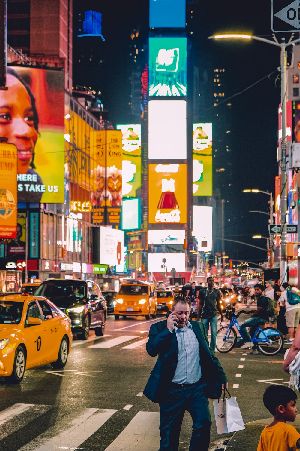 a man walking across a street holding a cell phone to his ear