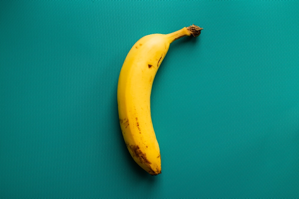 una banana matura seduta sopra una superficie verde