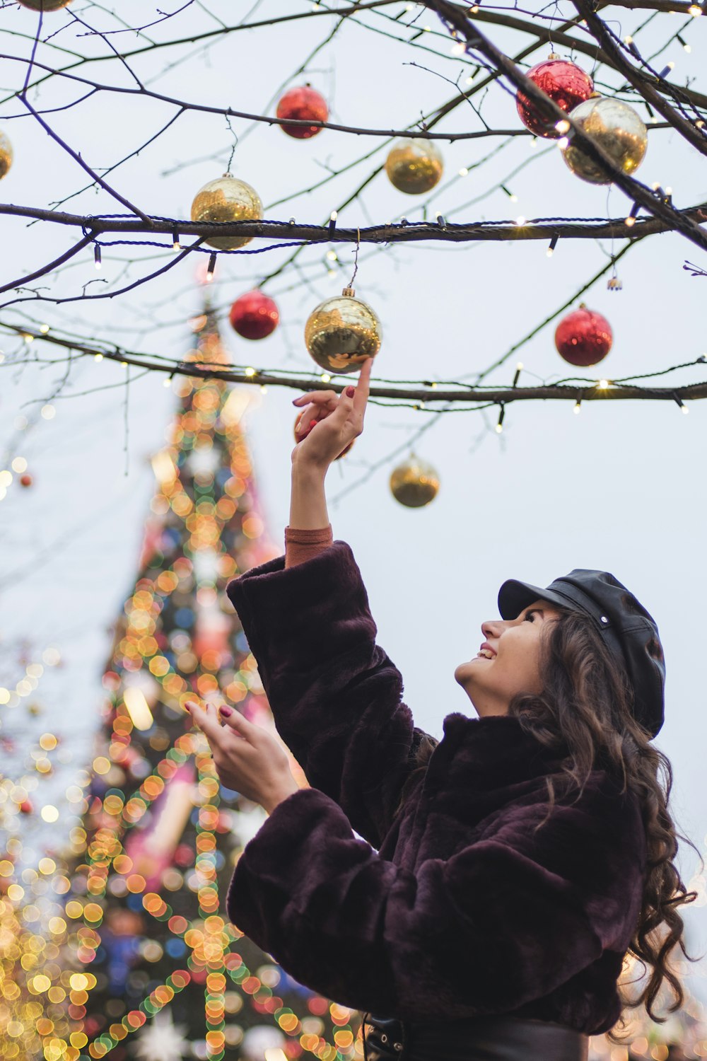 a woman in a black coat and a tree with christmas ornaments