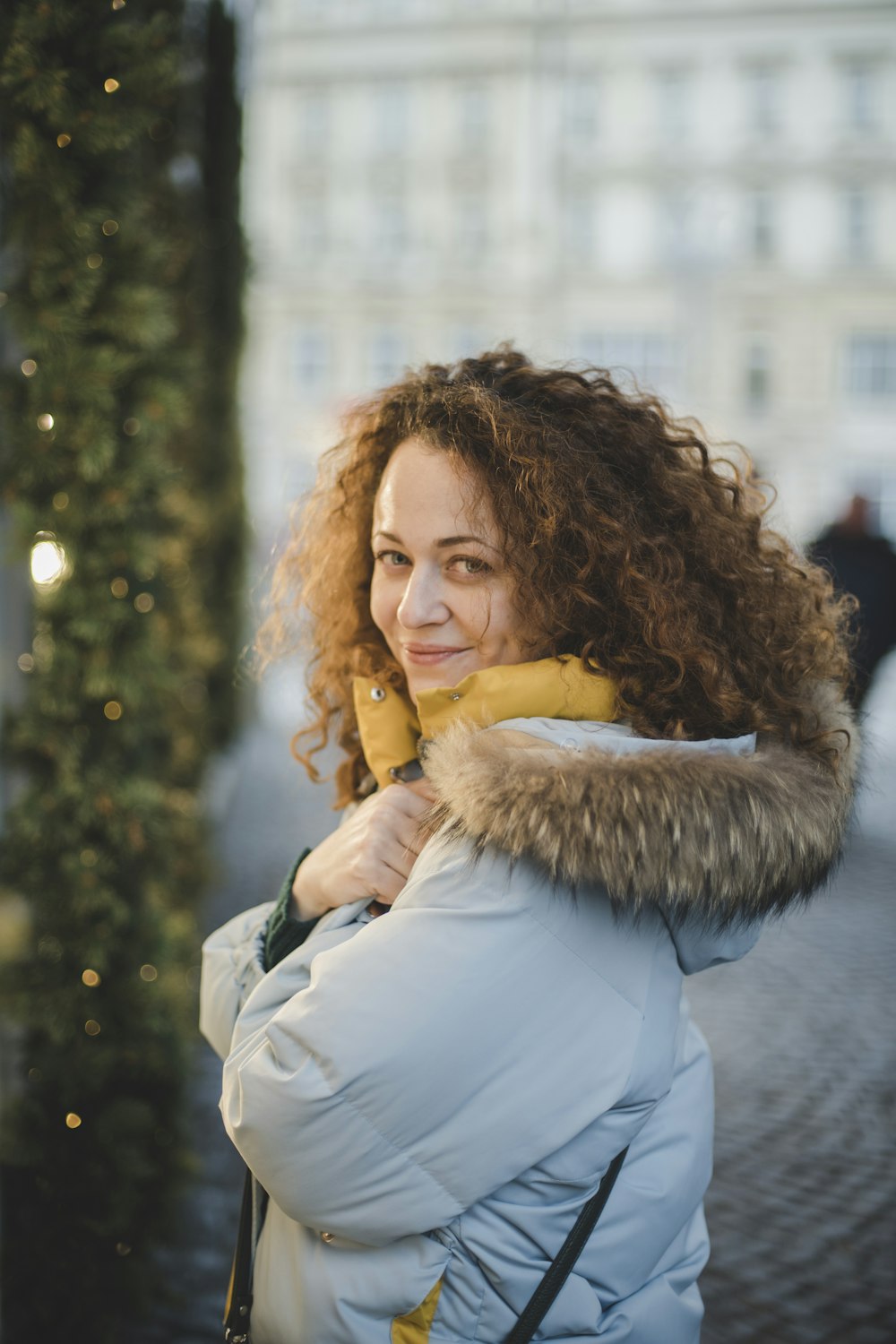 a woman with curly hair wearing a white coat