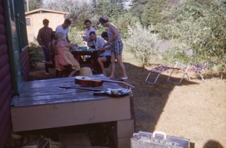 A group of people enjoying music outdoors with multiple wireless speakers placed around a picnic setup