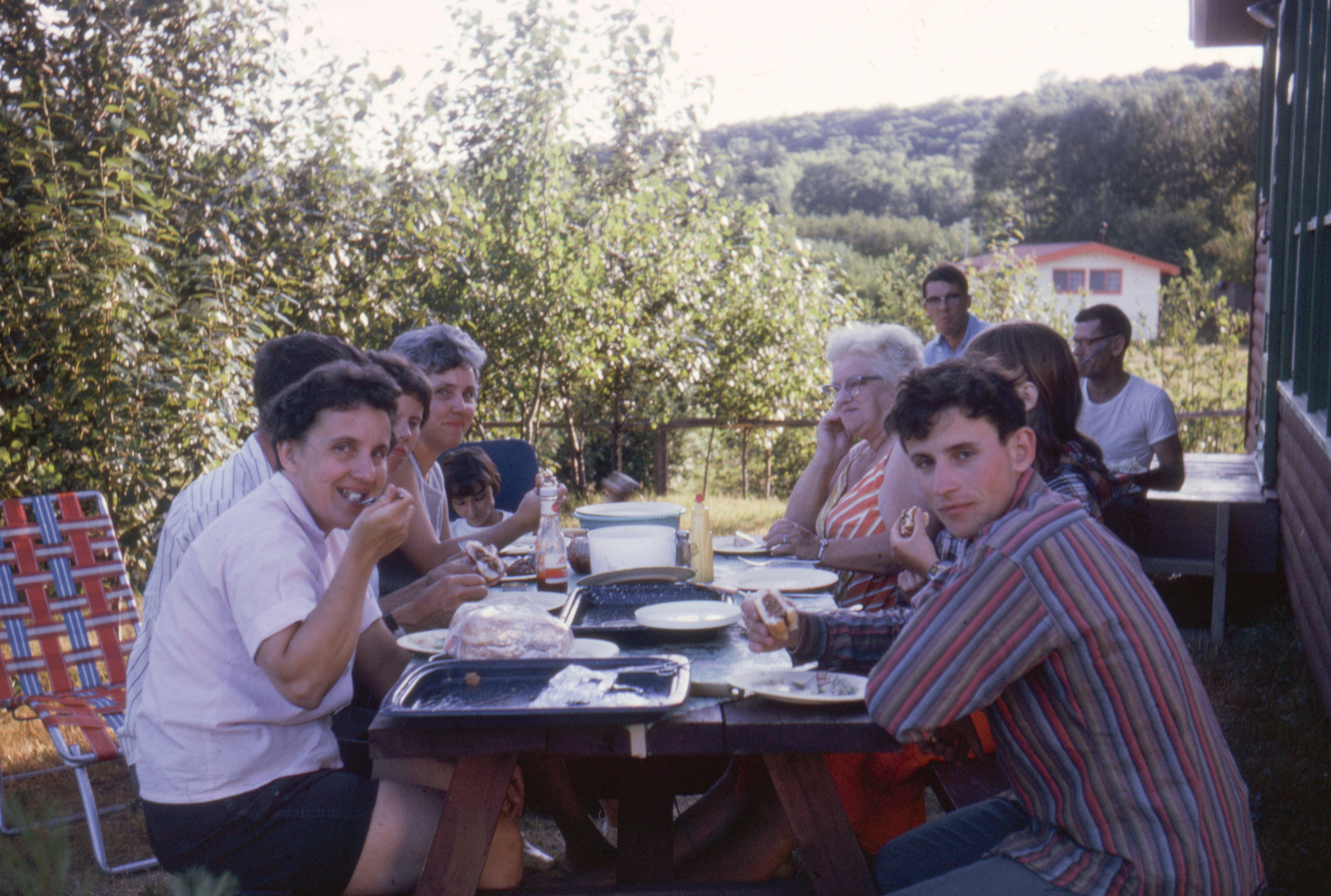 Familia comiendo junta en una mesa de picnic de madera al aire libre.