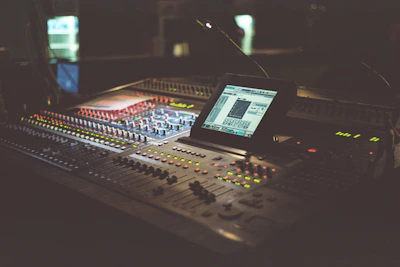 A sleek studio setup featuring mixing equipment illuminated by soft, dark ambient light.