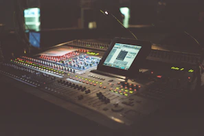 A warmly lit control room with mixing consoles glowing under soft blue lights.