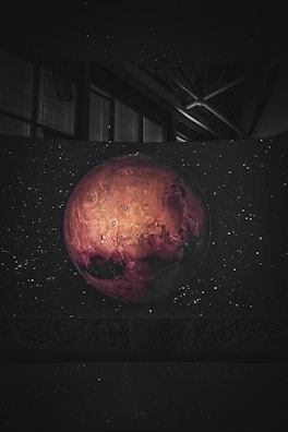 A detailed shot of the surface of Mars showing its reddish terrain and rocky formations under a clear sky.