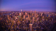 An aerial perspective of a bustling city skyline with skyscrapers glowing under twilight.