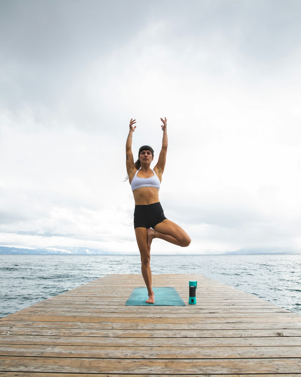 a woman doing a yoga pose on a dock