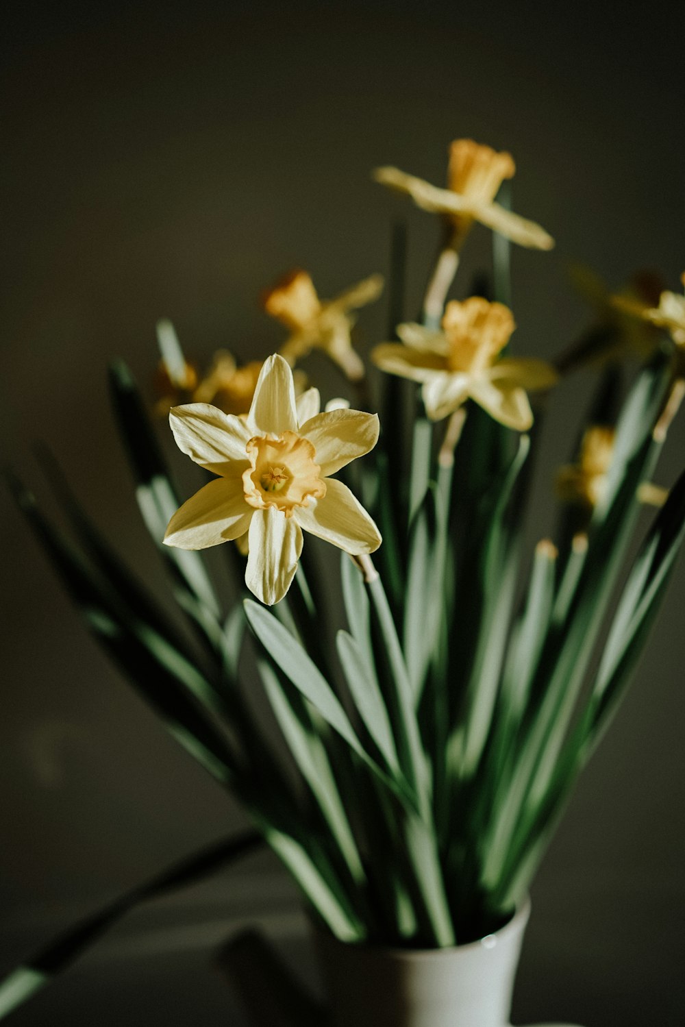 a white vase filled with yellow flowers on top of a table