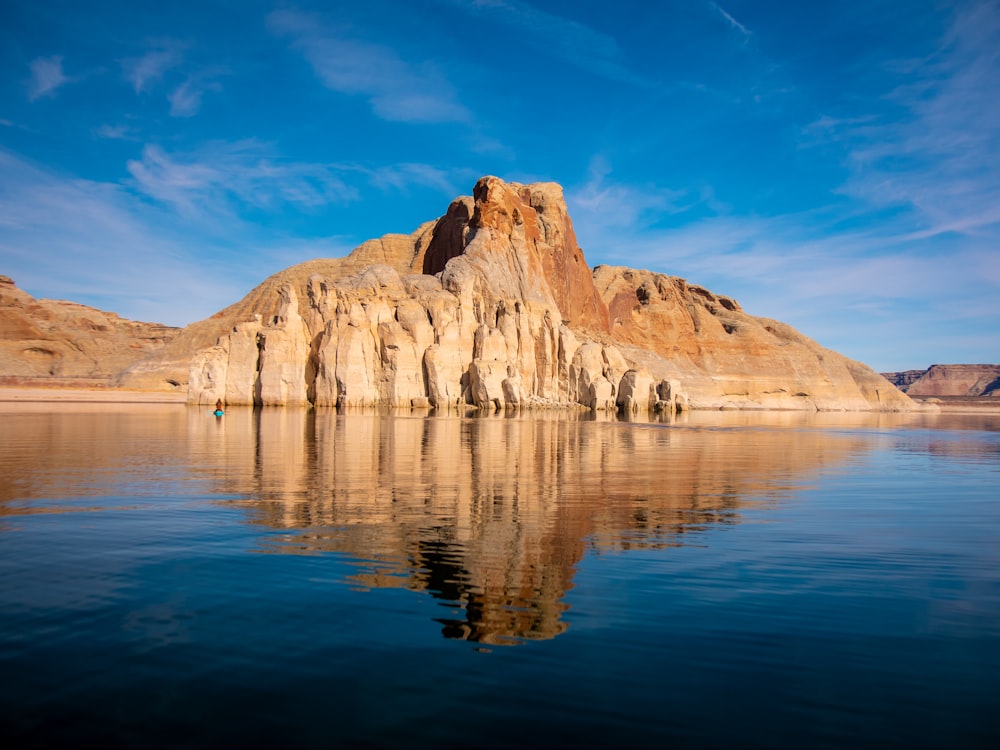 brown rock formation on body of water under blue sky during daytime