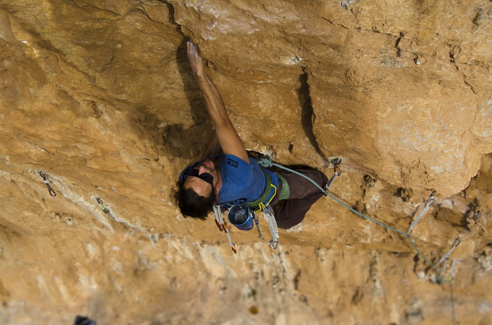 man climbing on brown rock