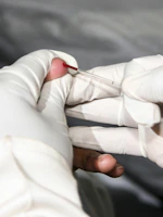 Friendly staff member taking a blood sample at a patient's home.