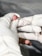 A gloved hand is holding a small lancet near a person's fingertip, with a drop of blood visible on the finger. The focus is on the finger prick procedure.