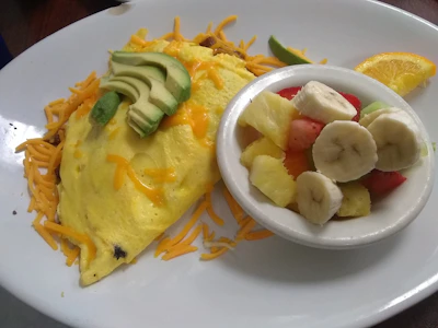 A colorful breakfast plate with omelette, fresh fruit, and coffee.