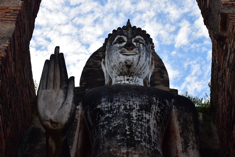 statua del drago in cemento marrone sotto il cielo blu durante il giorno