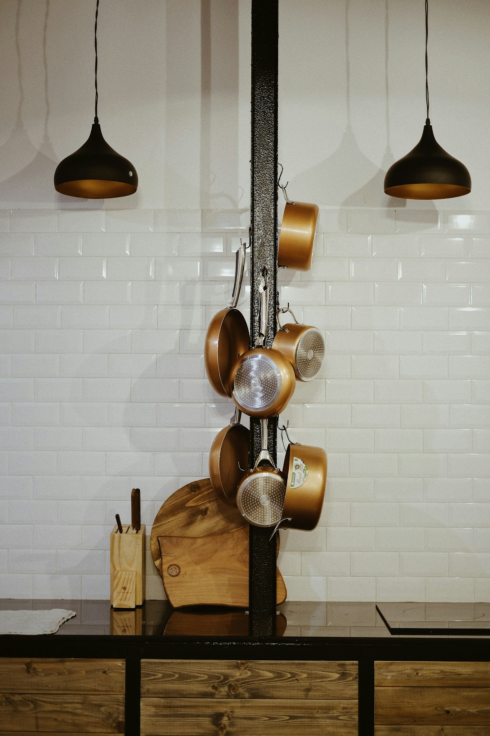 An overhead view of a colorful kitchen scene featuring several frying pans of different sizes arranged on a rustic wooden table.