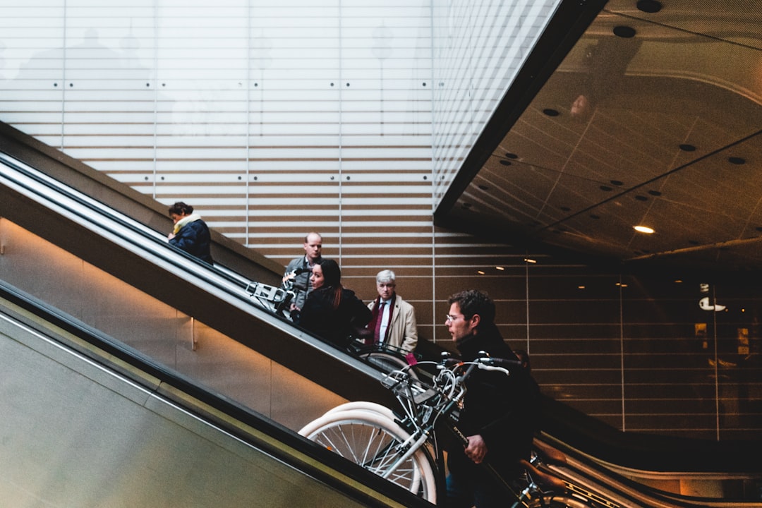 man in black suit jacket and black pants sitting on black and silver escalator