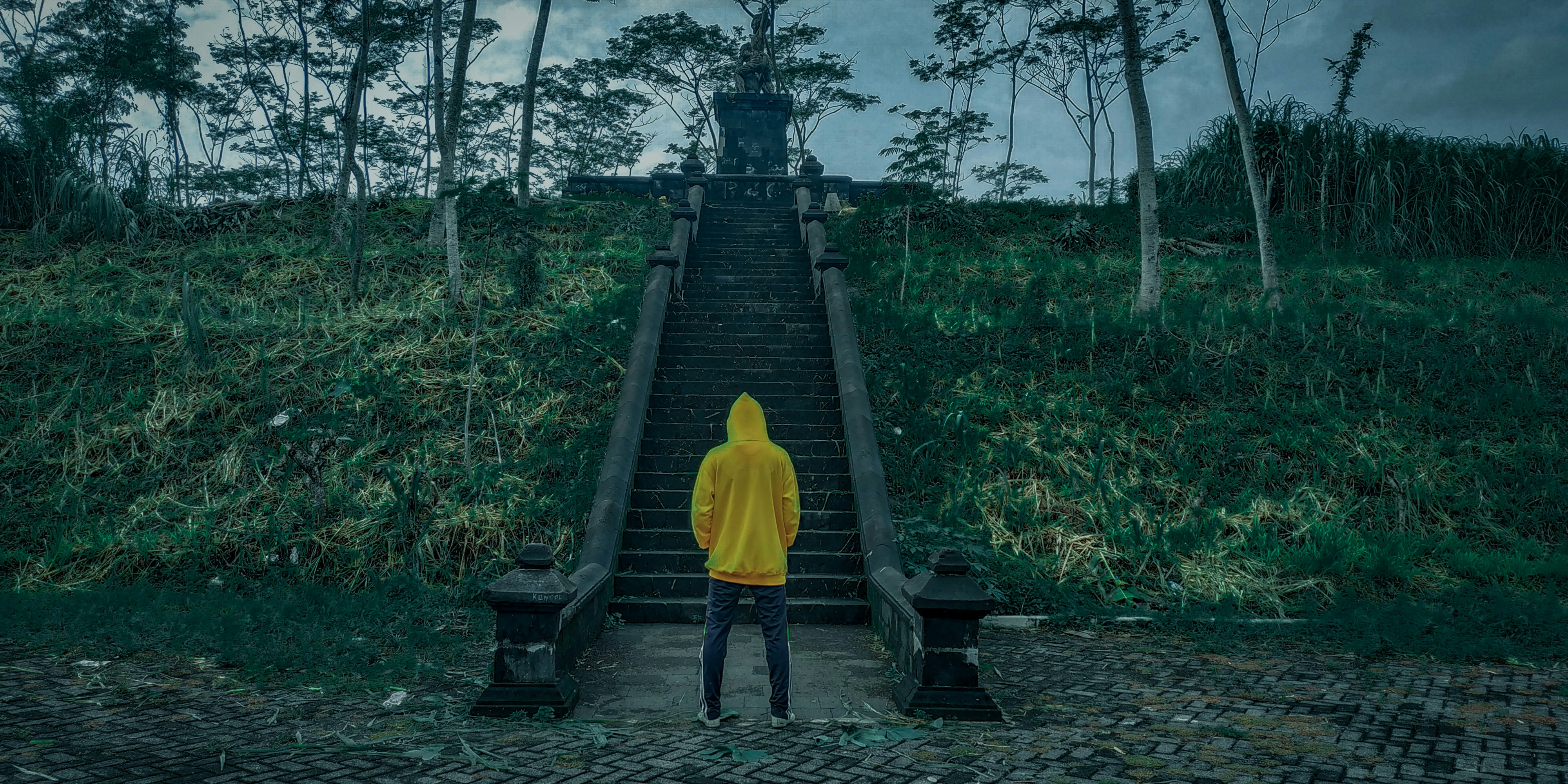 person in yellow hoodie walking on wooden bridge