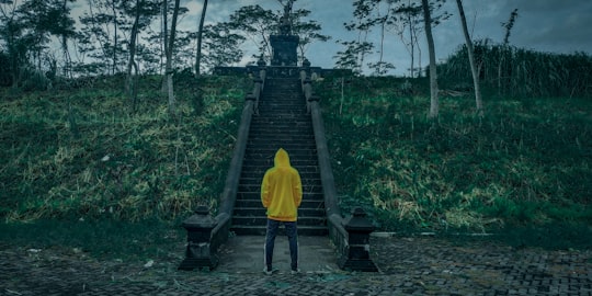 person in yellow hoodie walking on wooden bridge in Banjarnegara Indonesia