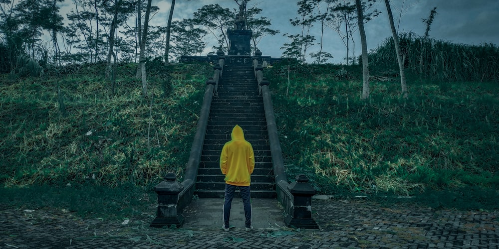 person in yellow hoodie walking on wooden bridge