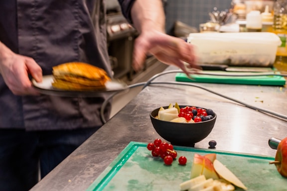 A cozy kitchen scene with a chef plating a colorful, fresh meal at a client's home.