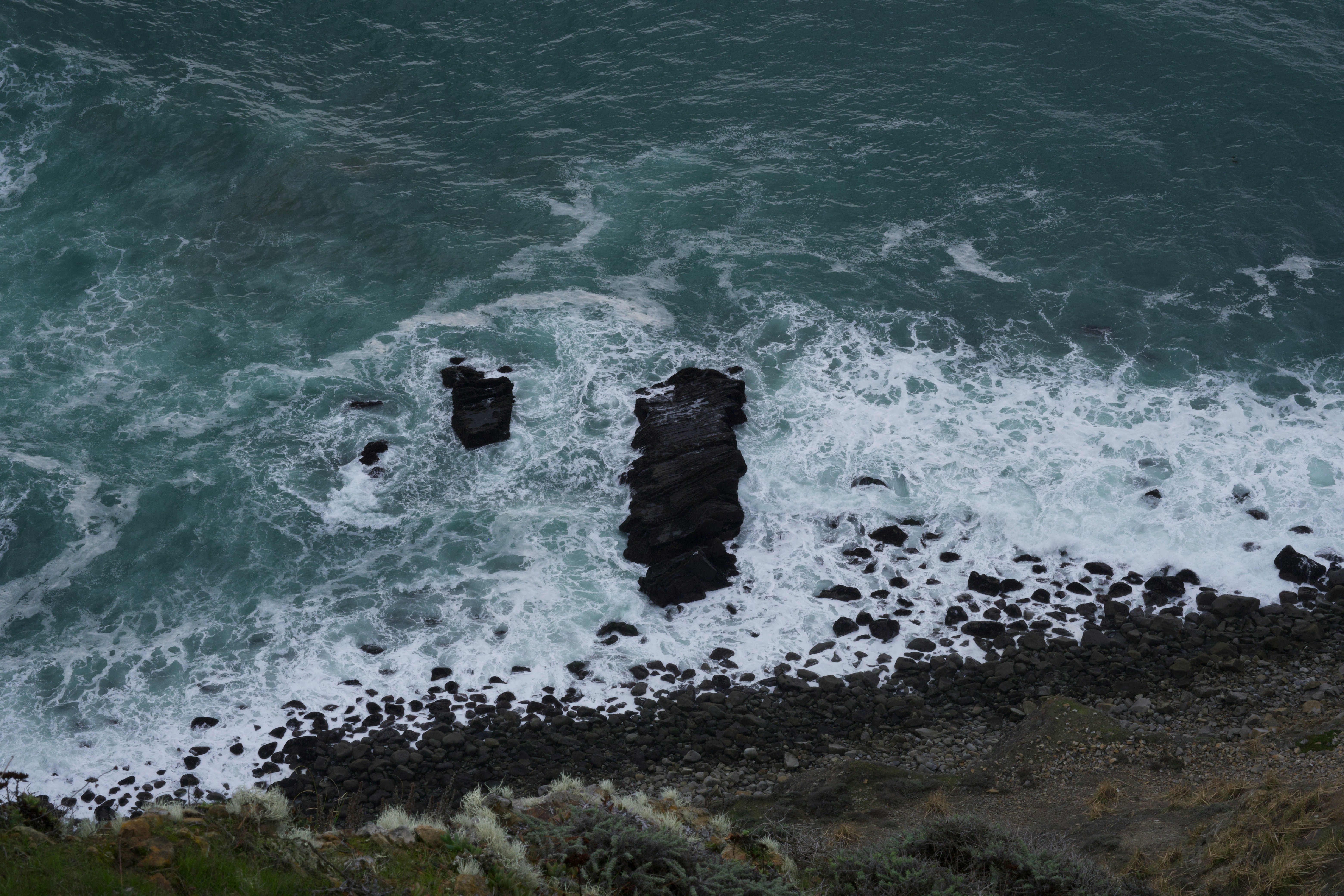 昼間の水域の黒い岩層