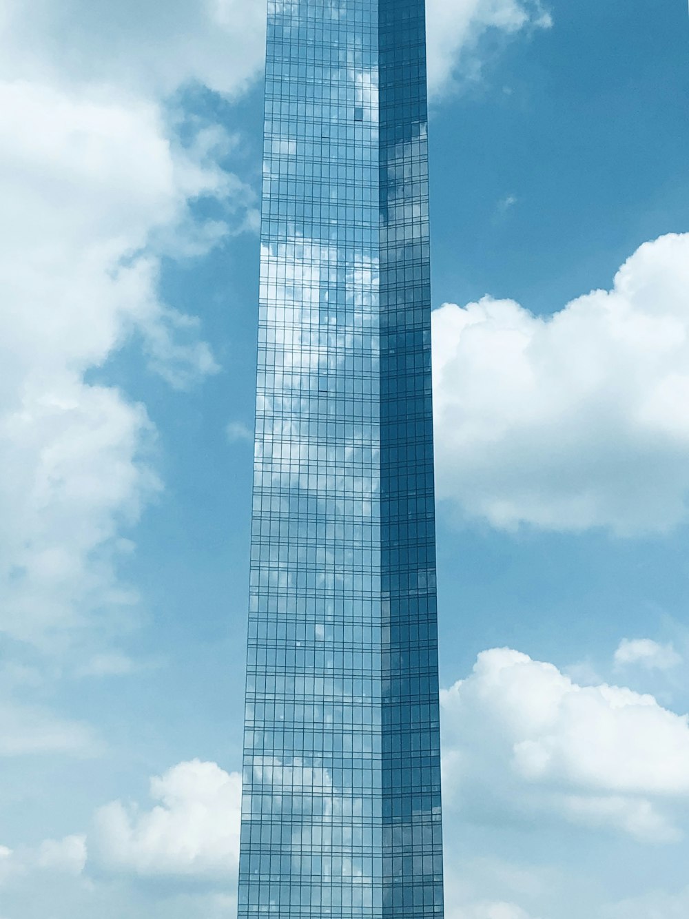 blue and white clouds over blue glass building