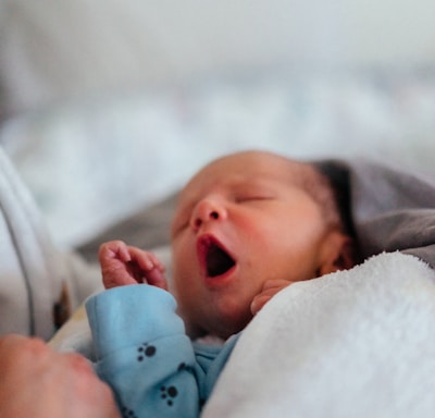 baby in white and blue onesie lying on bed