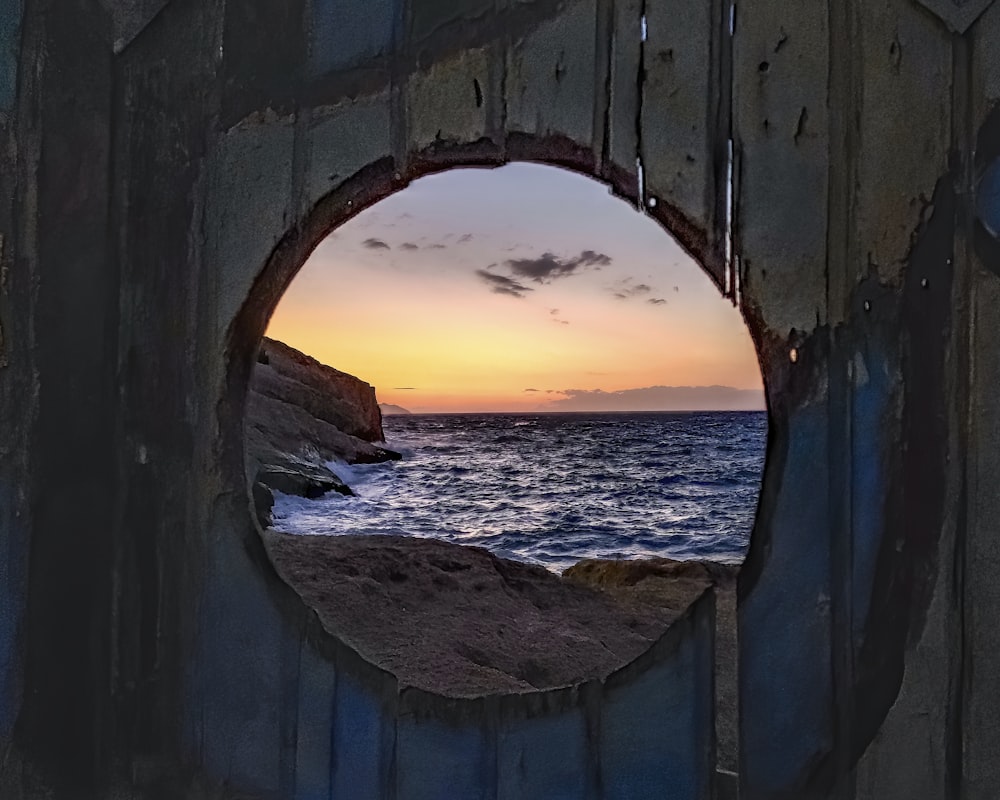 a hole in a wall with a sunset in the background
