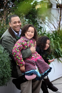 Smiling family relaxing indoors comfortably with air conditioning running, surrounded by green plants