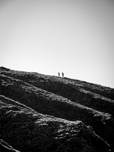 grayscale photo of person walking on hill