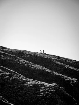 grayscale photo of person walking on hill