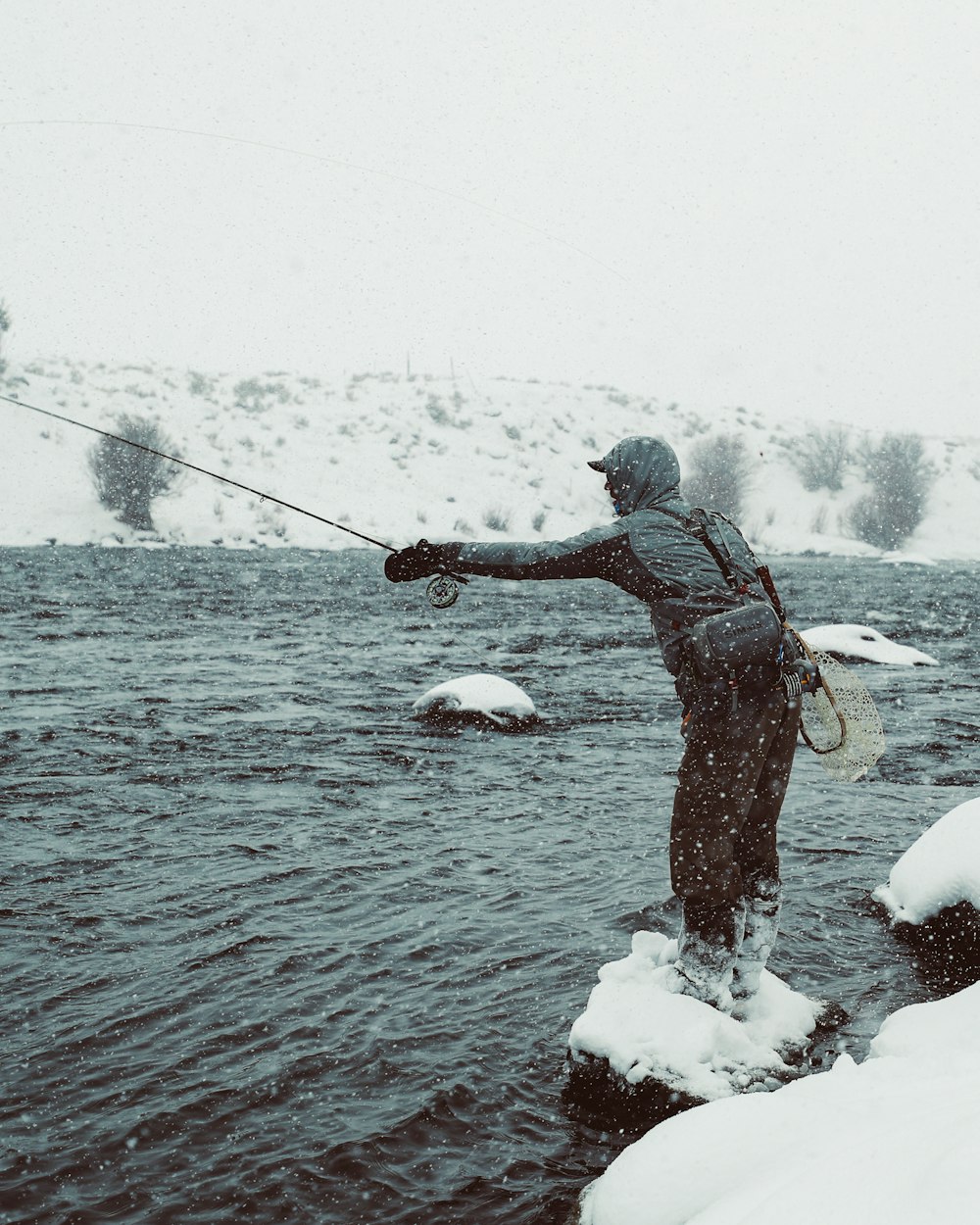 man in black jacket fishing on lake during daytime