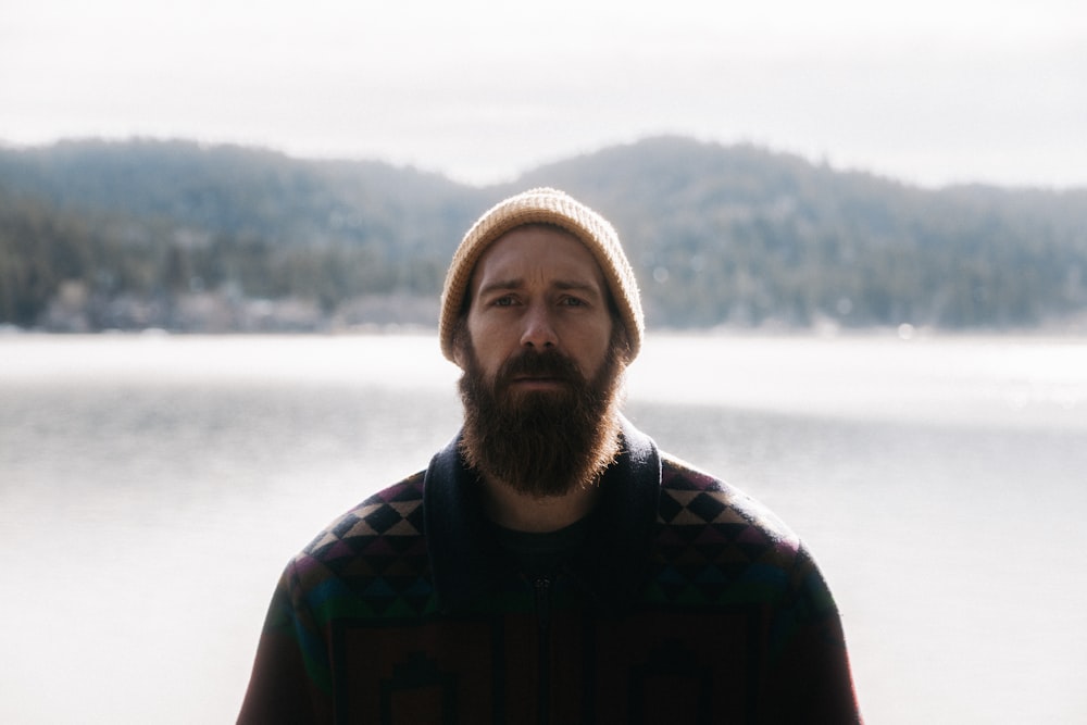 Un uomo con la barba in piedi di fronte a un lago