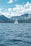 white sailboat on sea near mountain under white clouds and blue sky during daytime