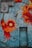 A mosaic design featuring vibrant, abstract floral patterns in shades of red, orange, and yellow on a blue tiled background. The artwork appears to cover a wall with a rusty metal window and a weathered door, contributing to an urban aesthetic.