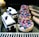 A variety of pastries, including berry-topped tarts with raspberries and blueberries, chocolate and cream cakes with cherries, and glazed éclairs, are displayed on a reflective black surface.