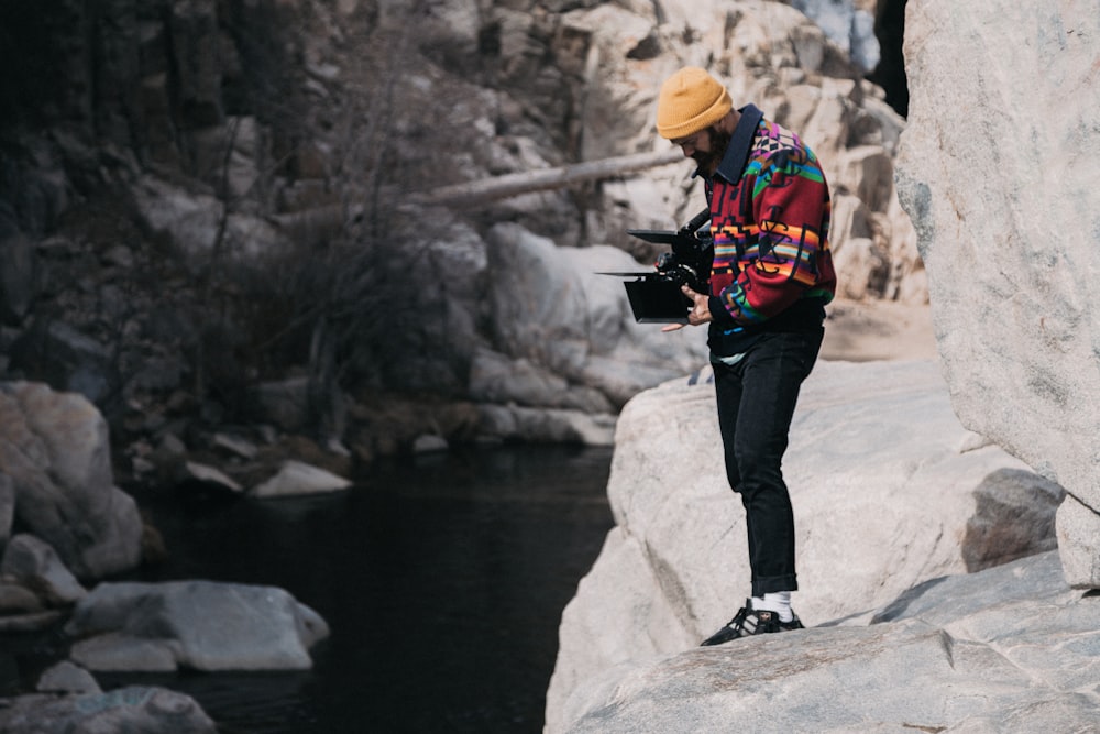 a man standing on a rock next to a river