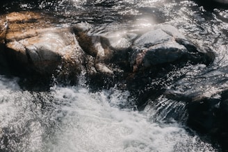 water falls on rocky shore during daytime