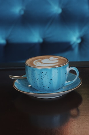 A pastel blue ceramic cup filled with a frothy, aromatic coffee topped with latte art.