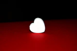 A close-up of a heart-shaped donation counter glowing softly on a wooden table.