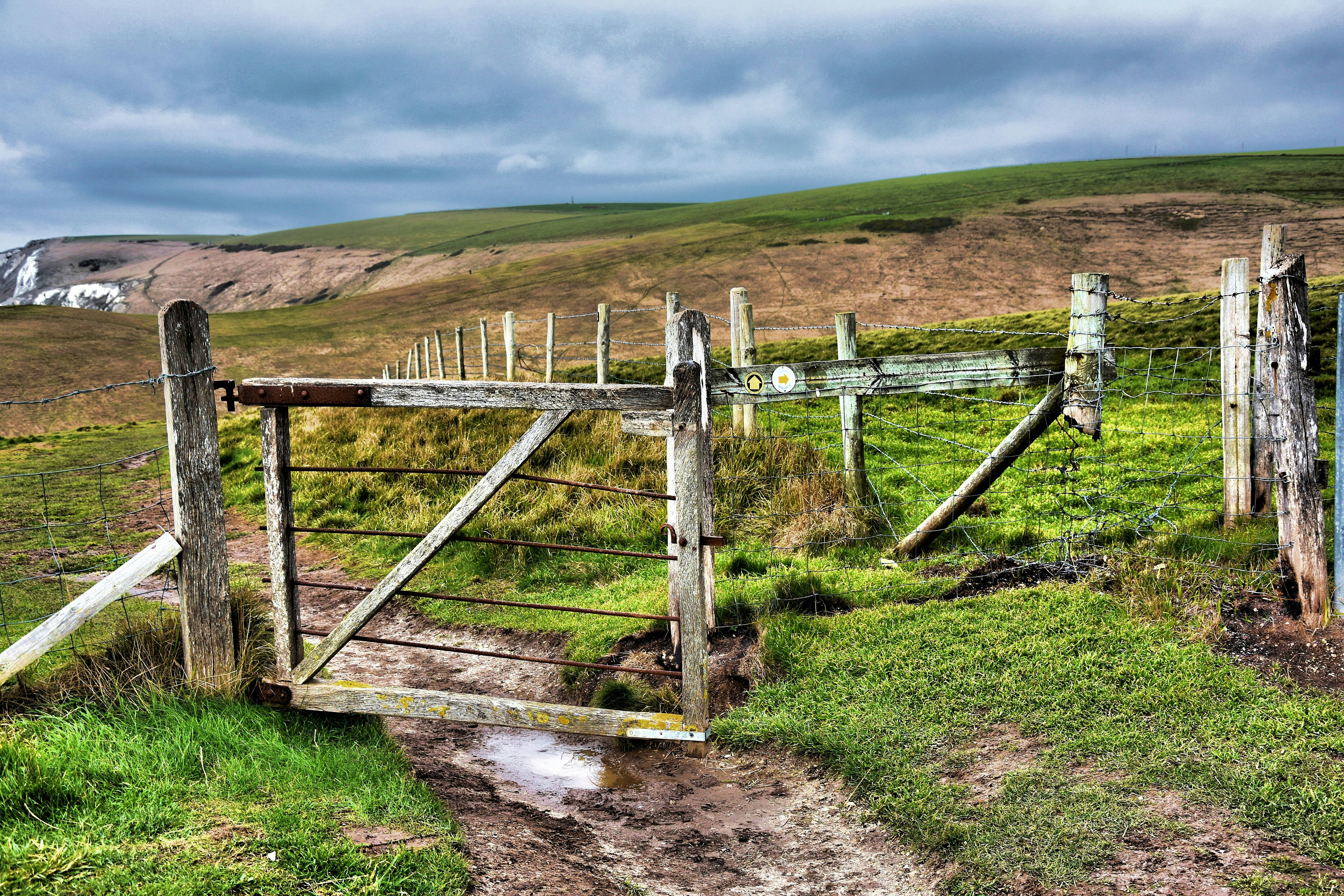 brown wooden fence on green grass field under blue sky during daytime