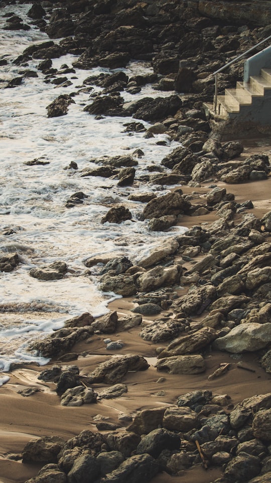 brown rocks on seashore during daytime in Estoril Portugal